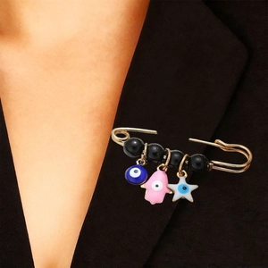 Détail de la broche dorée œil porte-bonheur avec main de Fatima sur veste noire