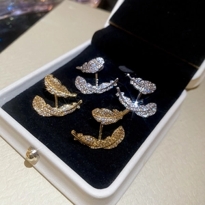 Close-up of gold and silver leaf feather earrings with zircons on black velvet box