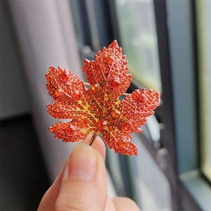 Detailed close-up of a luxury maple leaf brooch with orange and red crystal rhinestones