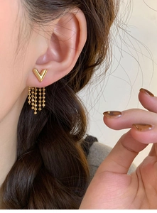 Detailed close-up of gold V-shaped tassel earrings on model with elegant hanging chains