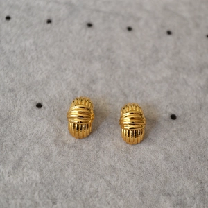 Detail of gold-plated striped stud earrings on grey felt surface with minimalist design