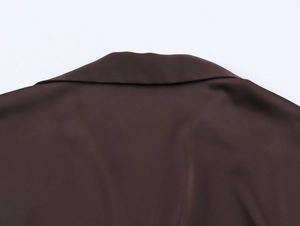 Détail du col d'une chemise en satin marron foncé avec texture lisse et coutures