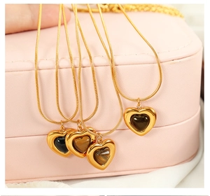 Close-up of heart-shaped tiger eye stone pendants on golden snake chains in a pink box