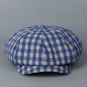 Detail of the blue-grey plaid newsboy cap showing the top button and linen texture