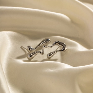 Minimalist silver liquid drip irregular stud earrings on cream silk background