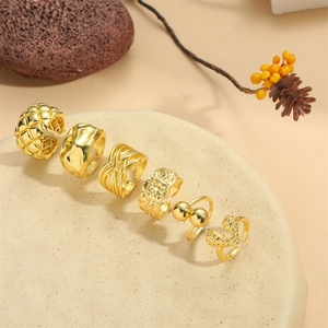 Set of six gold hammered texture adjustable rings and ear cuffs on a decorative plate