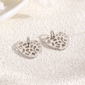 Detailed macro view of two silver hollow heart charms for DIY jewelry making and necklaces