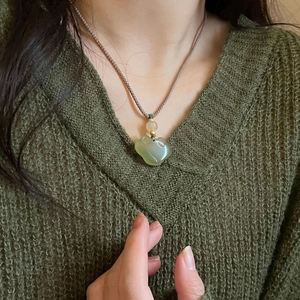 Detailed view of hand-woven cord and green jadeite lucky cloud pendant on a model
