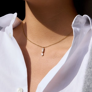 Detailopname van een gouden 18K ketting met een verticale druppelvormige zirkoon