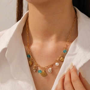 Gold-plated ocean theme paperclip chain necklace with shells and pearls worn by a model