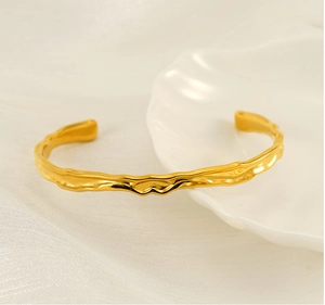 Macro shot of gold lava texture stainless steel bangle on white shell plate