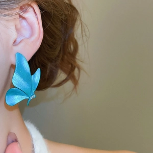 Close-up of blue butterfly drop earring with delicate bionic texture and white crystals