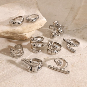 Polished silver geometric stainless steel rings on a natural stone base