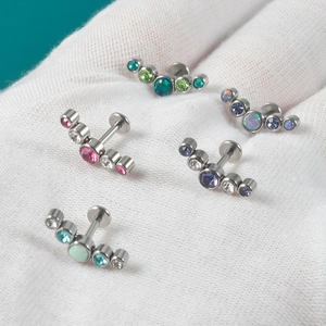 Detailed macro of five silver 16G lip rings with multi-colored opal and gemstone studs