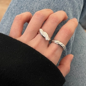 Close-up of minimalist 925 sterling silver knotted and spiral rings worn on finger