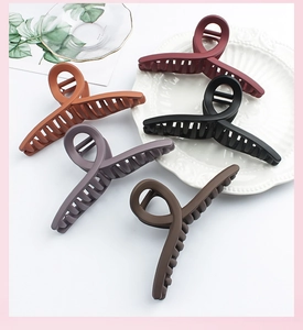 Flat lay of five matte large hair claws in burgundy and caramel colors on a tray