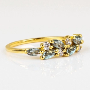 Detailed close-up of golden leaf ring with blue marquise gems and small diamonds