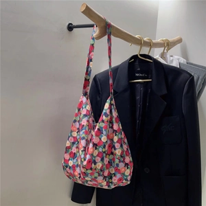 Detail of floral print cotton tote bag hanging on wooden stand with suit background