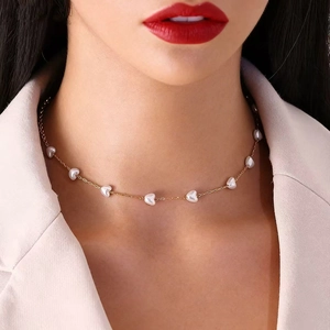 Primer plano de un elegante collar de acero inoxidable con perlas en forma de corazón.