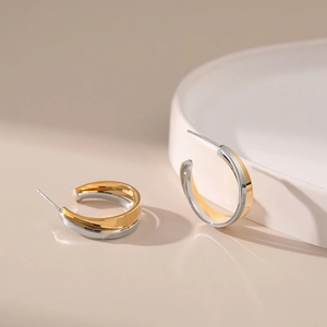 Minimalist gold and silver two-tone C-shaped earrings with interlocking metal design