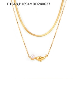 Détail du collier double rang en titane doré avec pendentif dauphin et perle