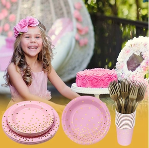 Pink and gold dot party tableware set with paper plates and cups in a festive setting