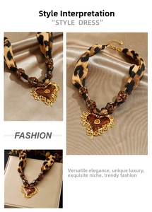 Détail d'un collier en tissu imprimé léopard avec un pendentif en forme de cœur doré vintage