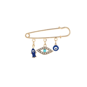 Detail of gold safety pin brooch with blue evil eye charms and rhinestone accents