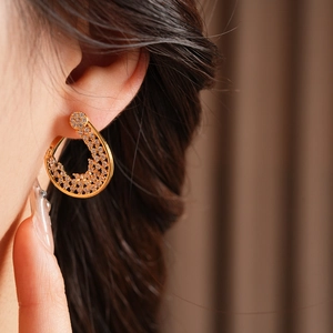 Detailed close-up of a gold-plated flower hoop earring with sparkling zircon stones