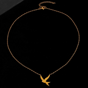 Détail du pendentif hirondelle dorée sur une chaîne fine avec fond noir élégant