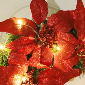Sparkling red Christmas poinsettia with warm LED lights and green pine needles decoration