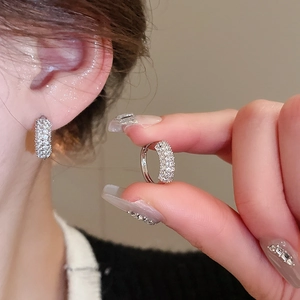 Close-up of small silver hoop earrings featuring micro-paved clear zirconia on model