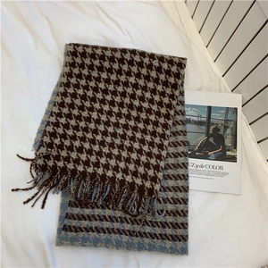 Detail of blue and brown houndstooth scarf with fringe on a white textured background