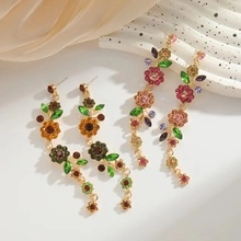 Close-up of colorful crystal flower drop earrings on a white marble display tray