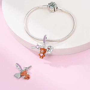Detailed macro view of silver snake chain bracelet with bear and Peace envelope charms