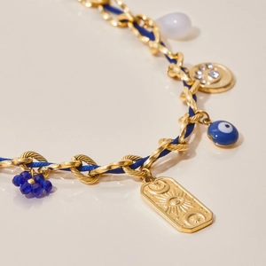 Macro shot of gold chain necklace with blue cord, celestial charms and blue eye pendant