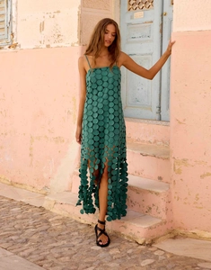 Detail of dark green midi dress featuring laser-cut hollow discs and tassel hemline