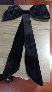 Detailed view of a large black velvet decorative butterfly bow with long hanging ribbons
