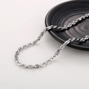 Macro detail of silver stainless steel pig nose chain link necklace on a black plate