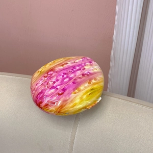 Macro detail of oval evening clutch with glossy pink and yellow marble texture finish