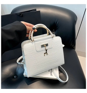 Détail du sac à main blanc motif crocodile avec pendentif cerf doré et poignée anneau