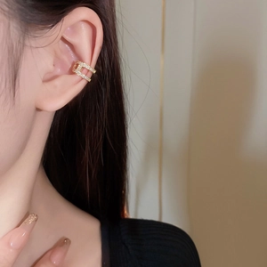 Detail of gold double-layer C-shaped ear cuff with sparkling zircon on model's ear