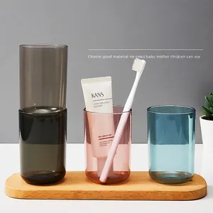 Three transparent plastic mouthwash cups on an oval wooden tray with a minimalist design