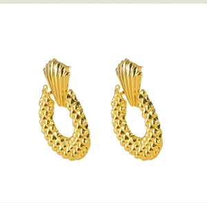 Macro shot of 18K gold plated geometric earrings with textured quilted patterns