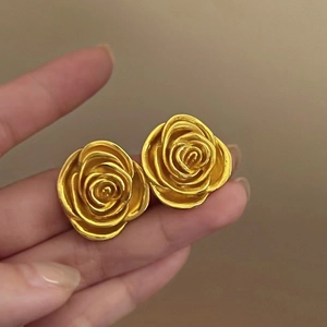 Close-up of gold-plated rose earrings with detailed three-dimensional petals