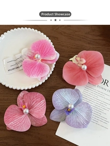 Detailed view of four orchid hair clips with white pearls on a rustic wood background