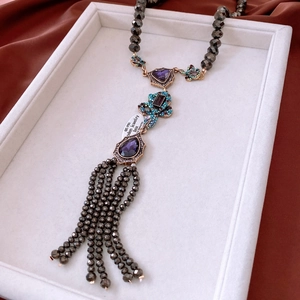 Detailed macro view of vintage long tassel necklace with purple teardrop gemstones