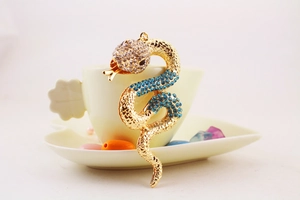 Detailed view of a gold-plated snake keychain with sparkling blue and white rhinestones