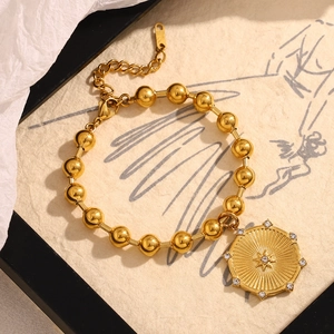 Dettaglio del bracciale a sfere placcato oro 18K con ciondolo a stella su carta