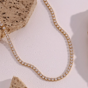 Macro shot of 14K gold plated tennis necklace with white zircon stones on stone background